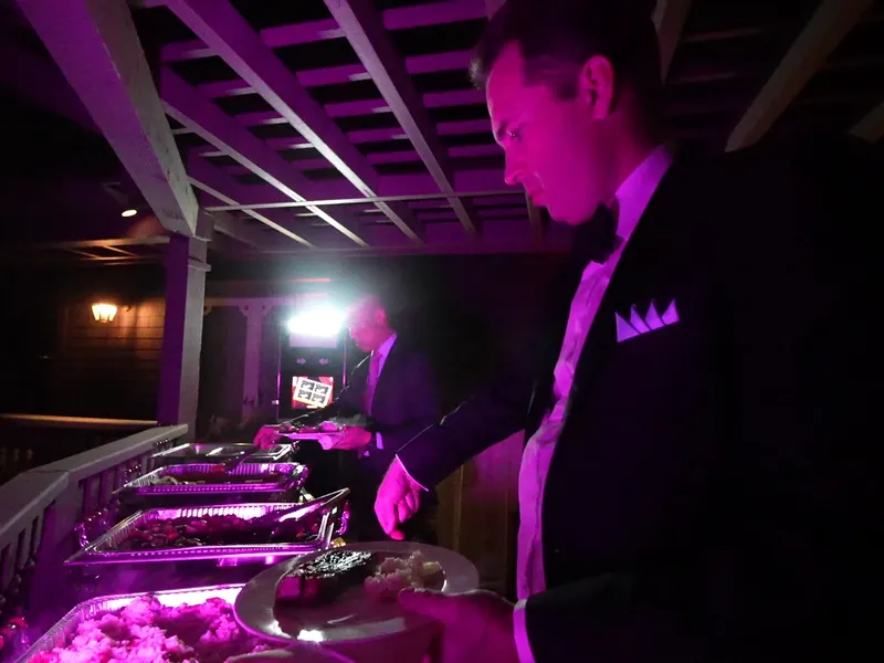 Buffet attendant serving guests under warm event lighting