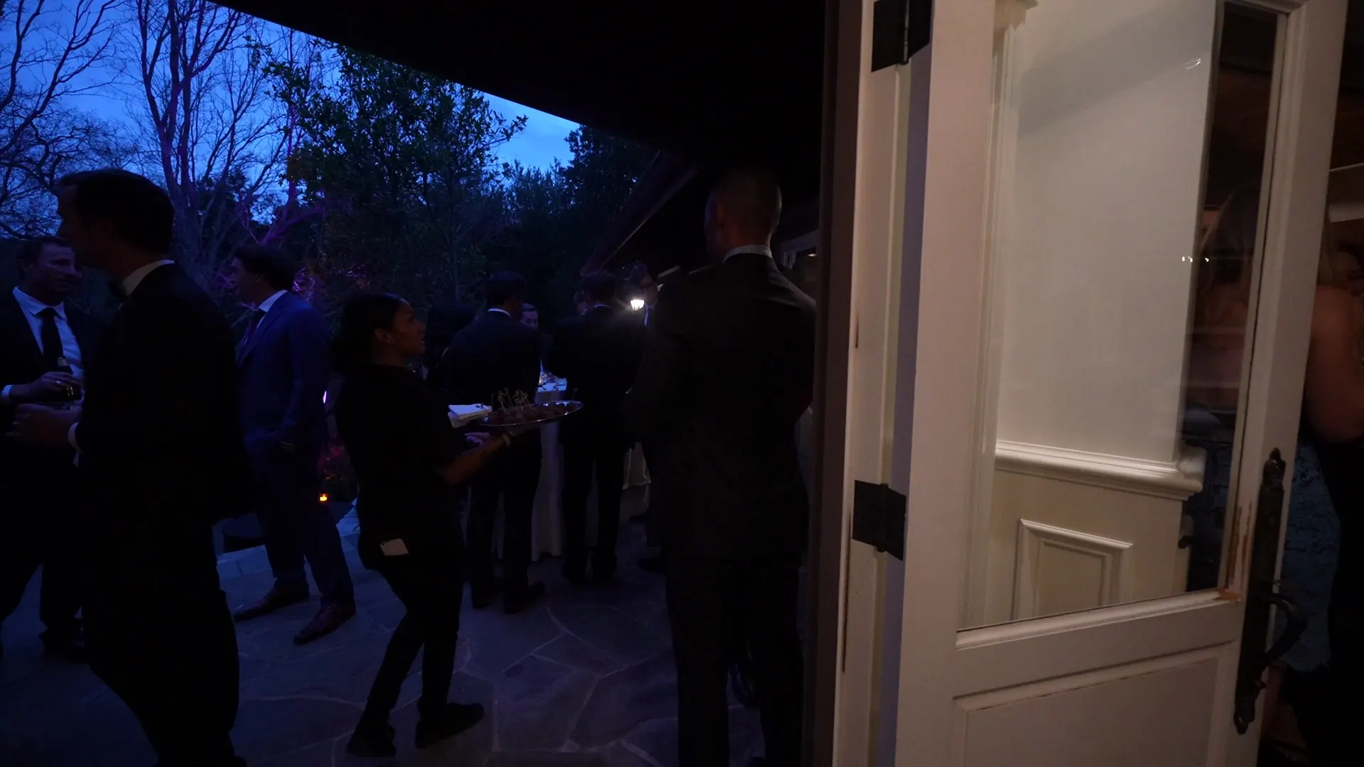 Guests at an evening cocktail hour as staff pass appetizers