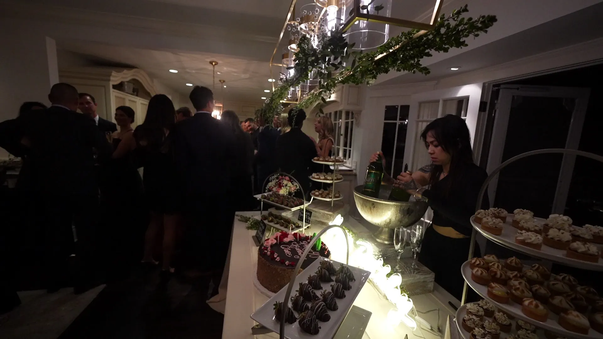 Lit dessert and appetizer display with guests gathered around