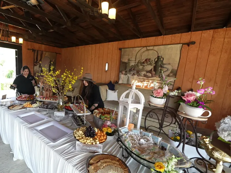 Long grazing table of charcuterie, cheeses, and florals in a wood-beam room