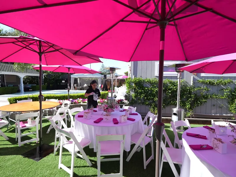 Garden party tables with pink umbrellas and floral place settings