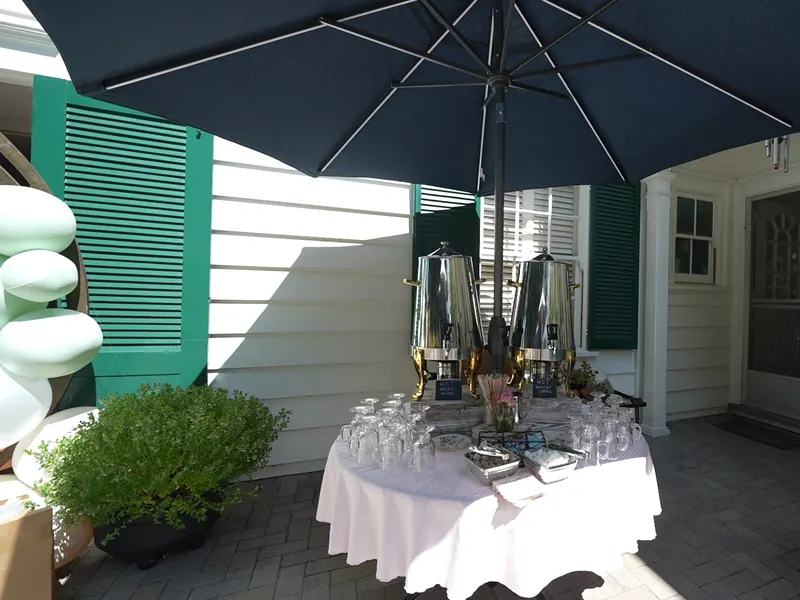 Patio beverage station with chilled bottles and glassware under a shade umbrella