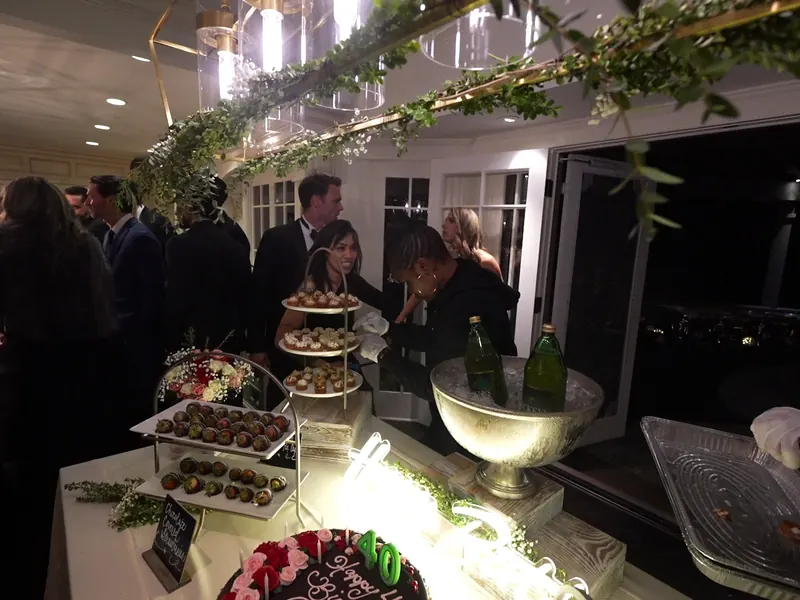 Guests mingling beside a lit dessert display at an evening reception