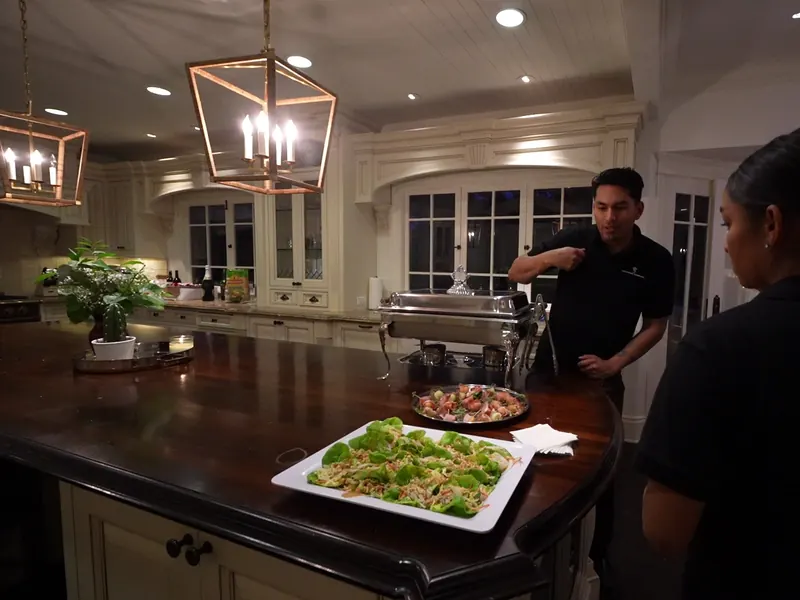 Staff arranging appetizer platters on a kitchen island before service