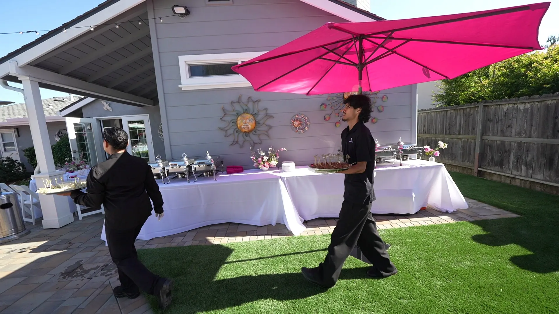 Attendants working a patio buffet under a bright shade umbrella