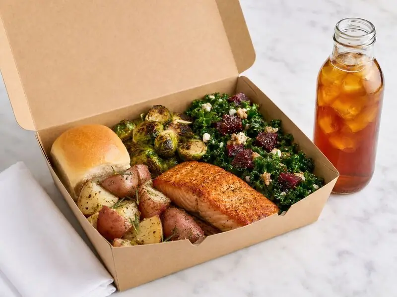 Boxed catering entrée of roasted salmon, red potatoes, seasonal vegetables, salad, roll and iced tea packed for a Sunol job-site lunch