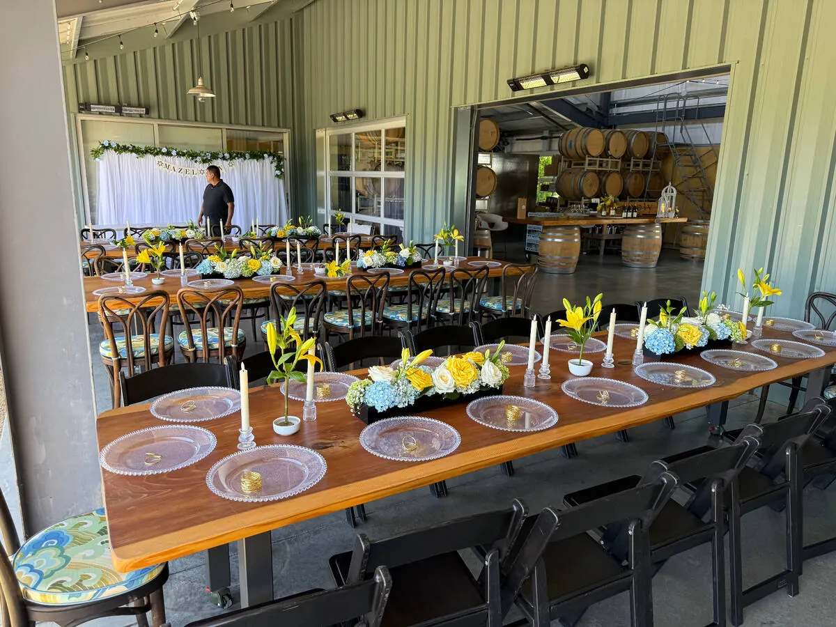 Long table running with lily, hydrangea and rose arrangements set between slim taper candles — centerpiece design for Sunol catering dinners