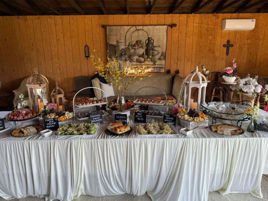 Grazing table of meats, sandwiches and fruit tarts punctuated by low seasonal arrangements down the linen — florals styled with Livermore catering displays