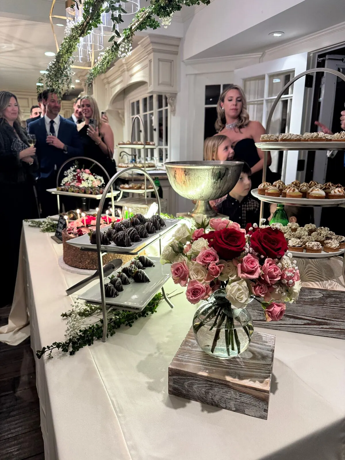 Wedding sweets table with garden roses tucked between chocolate-covered strawberries and pastries — wedding dessert florals in Pleasanton