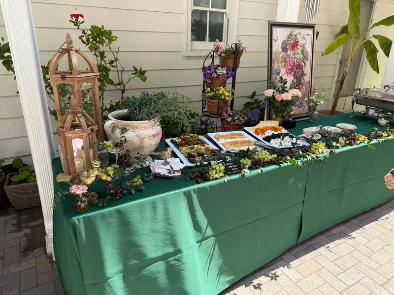 Garden-style private party appetizer buffet with cheeses, fruit, crackers and floral accents set up for a San Ramon backyard celebration
